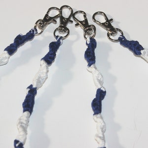 Peut inclure: Quatre lanyards tressés bleu marine et blancs avec des clips pivotants argentés.