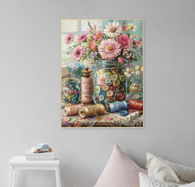 May include: A vintage-style painting of a glass jar filled with colorful buttons, surrounded by spools of thread and other sewing supplies. The jar is sitting on a table with a bouquet of pink and white flowers in the background.