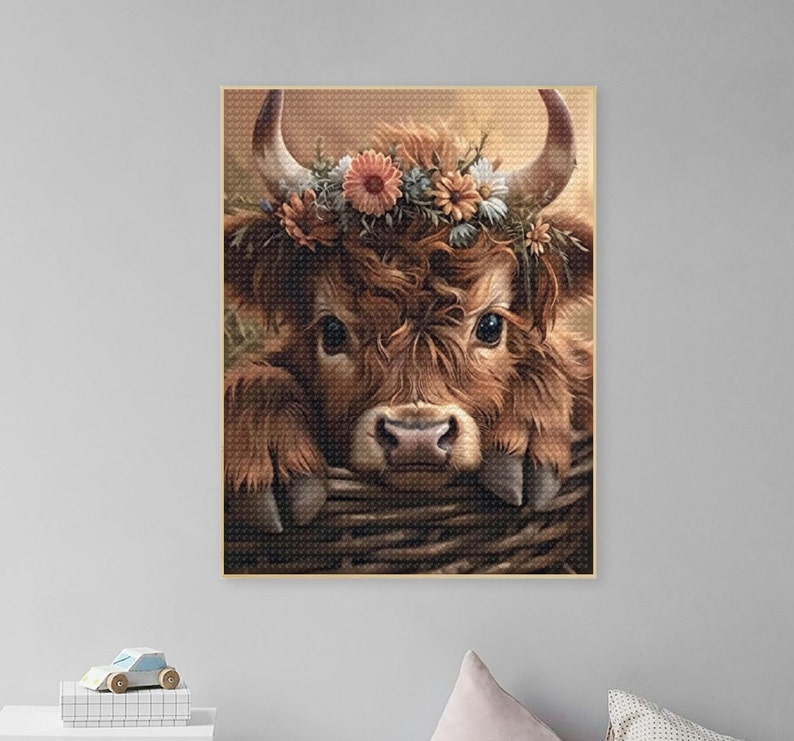 May include: A close-up of a brown and white cow with a flower crown. The cow is looking directly at the camera and has its head resting on a woven basket.