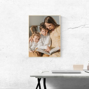 May include: A woman and two children sitting on a chair, reading a book together. The woman is wearing a light yellow dress and the children are wearing light blue shirts. The woman is smiling and the children are looking at the book.