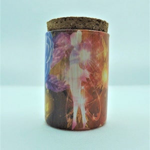 May include: A cylindrical wooden jar with a cork stopper. The jar is decorated with a colourful design featuring a silhouette of a figure, flowers, and abstract shapes in shades of red, orange, pink, and blue.