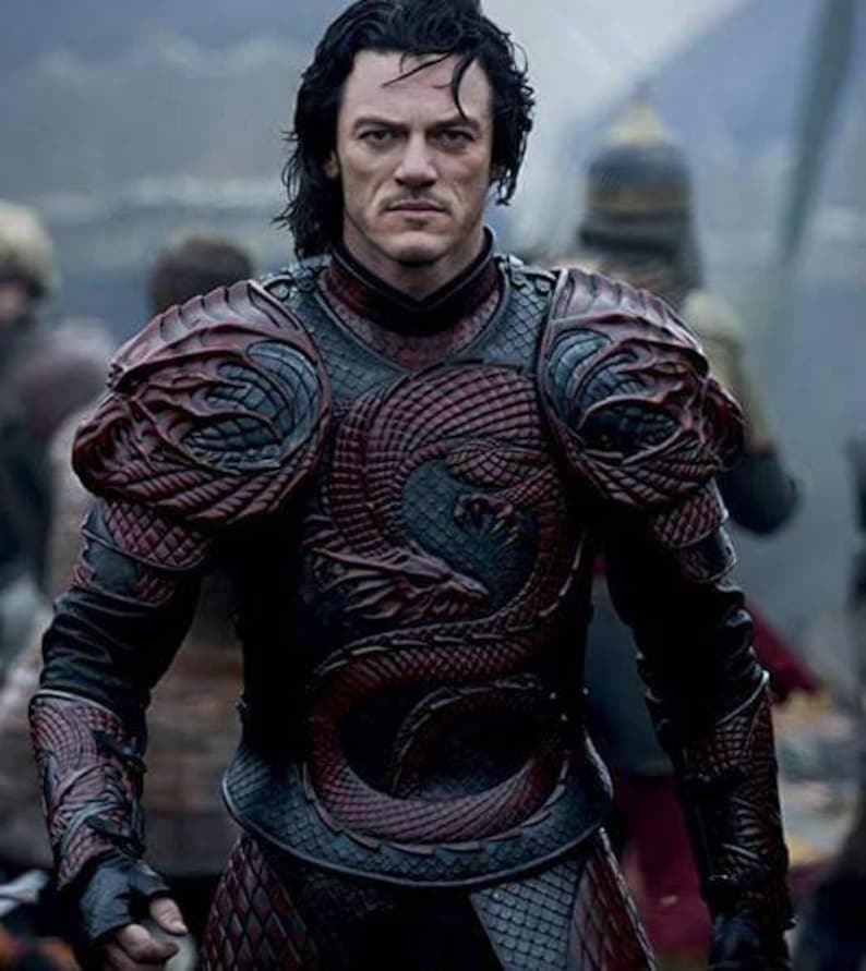 May include: A man wearing dark red and black dragon-scale armour with a detailed design. The armour has a high collar and covers the chest, shoulders, and arms.