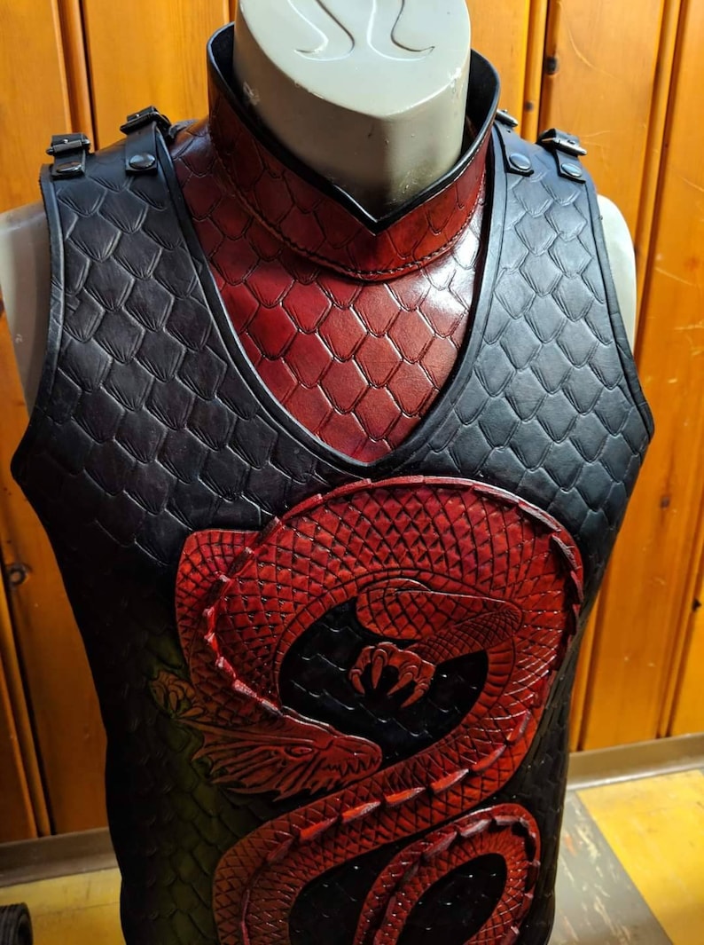 May include: A black leather vest featuring a red dragon design. The vest has a high collar and is decorated with a scale pattern.