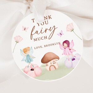 Puede incluir: Etiqueta redonda de agradecimiento con una ilustración de acuarela de hadas, mariposas y flores. El texto dice "Muchas gracias hada, Con cariño, Brooklyn".