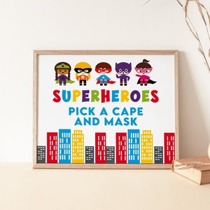 May include: A printable sign with a white background and a brown frame. The sign features a row of six cartoon superheroes in colorful costumes. The text reads "SUPERHEROES PICK A CAPE AND MASK" with a cityscape at the bottom.