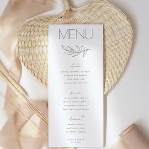May include: A white wedding menu card with a simple black line drawing of a branch with leaves. The menu includes the following items: Starter, Shrimp, Calamari, Scampi, Octopus and Mussels with Lemon and Extra-Virgin Olive Oil. Main, Three Double Cuts of Rack of Lamb Coated in an Aromatic Blend of Fresh Herbs and Spices. Dessert, Apple Crumble, Vanilla Ice Cream, Cinnamon Custard.  The card is on a white background with a woven heart-shaped fan and beige ribbon.