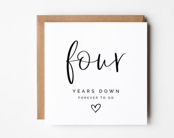 May include: A white card with black text that reads "four years down forever to go" with a small heart symbol.