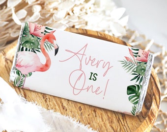 May include: Pink flamingo and tropical leaves printed on a white chocolate bar wrapper. The text "Avery is One!" is printed on the wrapper.