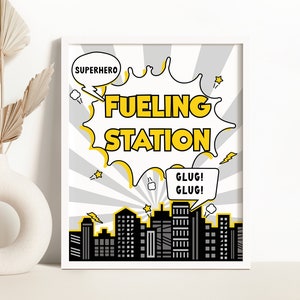 May include: A printable sign with a yellow and black comic book style design. The sign says "Superhero Fueling Station" with a speech bubble saying "Glug! Glug!" in a smaller speech bubble. The background is a gray and white cityscape.
