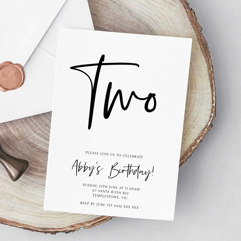 May include: A white invitation card with black text. The card says "Two" in a large, handwritten font. Below the number, it says "Please join us to celebrate Abby's Birthday!" and includes the date, time, address, and RSVP information.