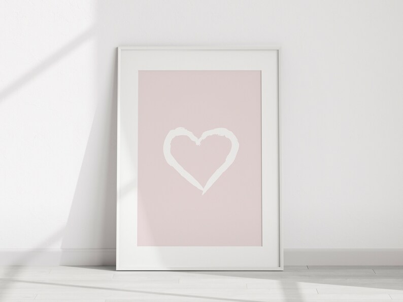 May include: A white framed print with a pink background and a white heart shape in the center.