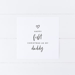 May include: A white card with black text that reads "Happy first Christmas as my daddy" with a small heart symbol above the text.