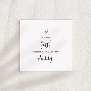 May include: A white card with black text that reads "Happy first Christmas as my daddy" with a small heart symbol above the text.