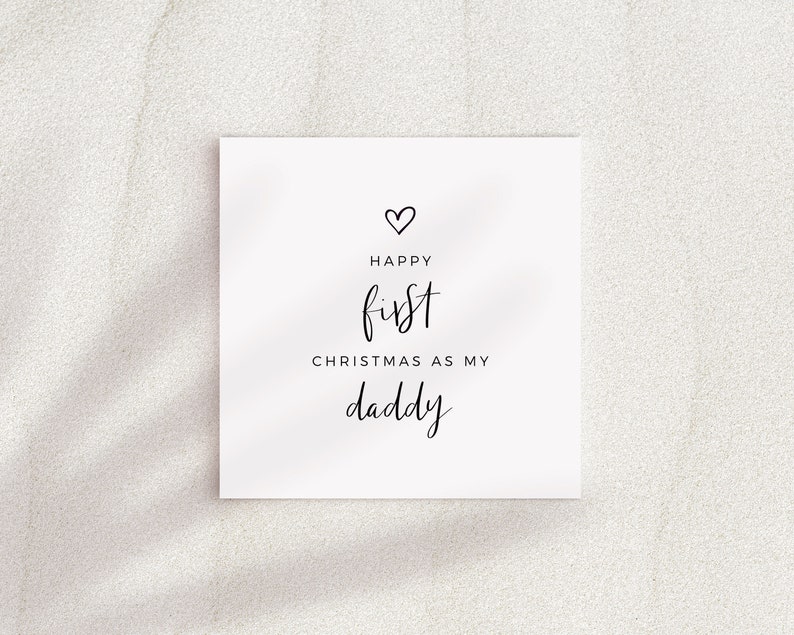 May include: A white card with black text that reads "Happy first Christmas as my daddy" with a small heart symbol above the text.