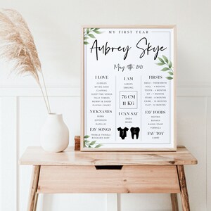 May include: A black and white printable chart for a baby's first year. The chart includes the baby's name, Aubrey Skye, and the date of birth, May 15th, 2021. The chart lists the baby's milestones, favorite foods, and songs. The chart is decorated with green leaves.