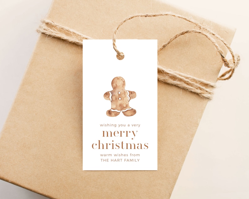 May include: A gift tag with a watercolor gingerbread man illustration. The tag reads "wishing you a very merry christmas" and "warm wishes from THE HART FAMILY". The tag is tied to a wrapped gift with twine.