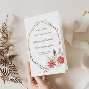 May include: A white wedding ceremony program with a gold geometric frame and floral accents. The text reads "Welcome to the Wedding Mass Uniting Margaret Ann Hall & Paul Beckett Wilde November 21, 2022 St. Mary's Church".