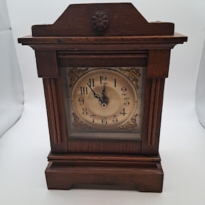 May include: A white ceramic mug with a black handle and the text "But First, Coffee" in a bold, black font. The mug is sitting on a wooden surface. The mug appears to be 12 ounces.