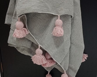 May include: A gray throw blanket with a white border and pink pom-poms.