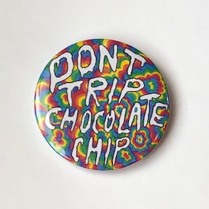 Könnte beinhalten: Ein runder Button mit dem weißen Schriftzug "DON'T TRIP CHOCOLATE CHIP" vor einem bunten, psychedelischen Hintergrund aus wirbelnden Mustern in Rot, Gelb, Blau und Grün.