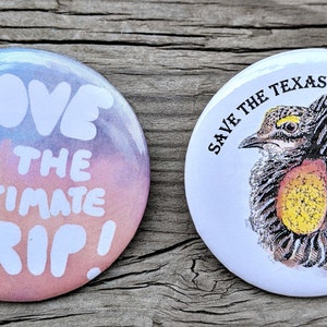 K&ouml;nnte beinhalten: Zwei runde Buttons. Einer hat einen bunten Hintergrund mit den wei&szlig;en Worten "LOVE IS THE ULTIMATE TRIP!". Der andere Button zeigt eine Zeichnung eines Pr&auml;riehuhns mit dem Text "SAVE THE TEXAS PRAIRIE CHICKEN" in Schwarz.
