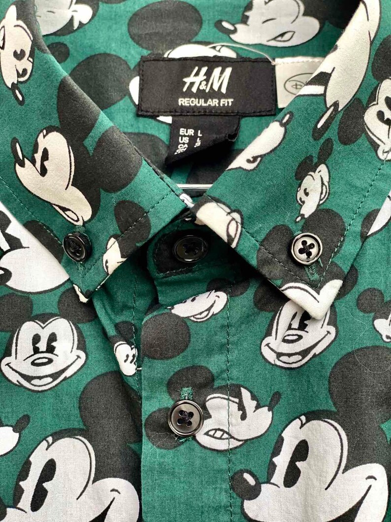 May include: A green button-down shirt with a Mickey Mouse print. The shirt has a label that says "H&M REGULAR FIT" and "EUR L US L CA L".