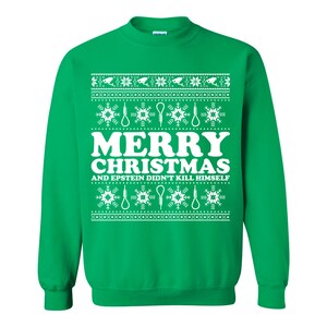 Może przedstawiać: Zielona bluza z białym napisem "MERRY CHRISTMAS AND EPSTEIN DIDN'T KILL HIMSELF". Wz&oacute;r zawiera płatki śniegu, pętle i kamery monitoringu w powtarzającym się wzorze.