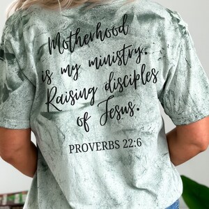 May include: A green tie-dye t-shirt with the text "Motherhood is my ministry. Raising disciples of Jesus. Proverbs 22:6" printed on the back.