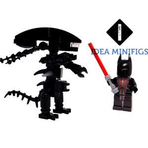 May include: A black Lego alien figure with a red lightsaber held by a black Lego Batman figure. The text "IDEA MINIFIGS" is visible in the background.