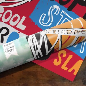 A roll of paper with various colorful and abstract designs printed on it, placed on a wooden surface.