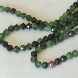 Peut inclure: Un brin de perles de pierres précieuses facettées vertes et roses. Les perles sont rondes et ont une finition lisse et polie.