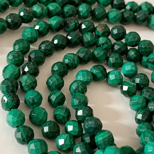 Peut inclure: Un brin de perles de malachite verte avec une finition facetée. Les perles sont rondes et ont un aspect naturel et terreux.