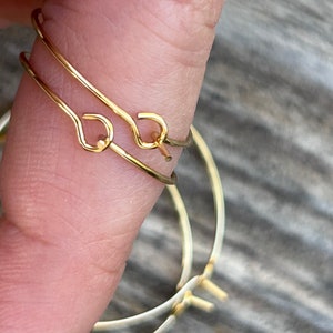 Puede incluir: Dos pendientes de aro dorados con un dise&ntilde;o simple y minimalista. Los aros est&aacute;n hechos de alambre fino y tienen un cierre de bisagra.