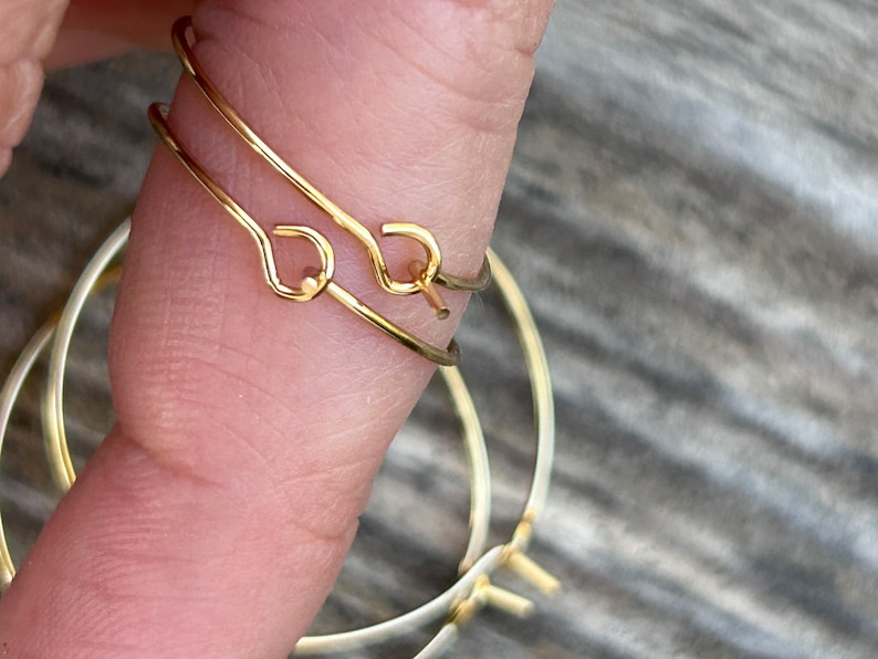 Puede incluir: Dos pendientes de aro dorados con un dise&ntilde;o simple y minimalista. Los aros est&aacute;n hechos de alambre fino y tienen un cierre de bisagra.