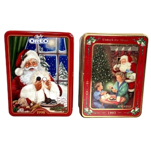 Op de afbeelding: Twee vintage Oreo-koekjestins. Eén tin toont de kerstman met Oreo-koekjes met de tekst "Only Oreo" en "1998". De andere tin heeft een kerstscène met de kerstman en de tekst "Unlock the Magic" en "1993".
