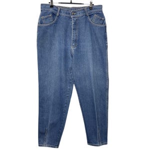 May include: Light blue denim jeans with a high waist and a classic five-pocket design. The jeans have a straight leg cut with a small slit at the ankle. The jeans are hanging on a metal hanger.