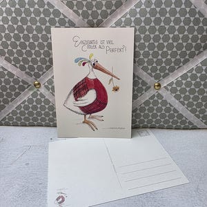 Könnte beinhalten: Eine Vintage-Postkarte mit einer skurrilen Vogelillustration. Der Vogel trägt eine rote Weste und einen karierten Rock und hält eine Blume. Der Text auf der Postkarte lautet: "Einzigartig ist viel cooler als Perfekt?!"