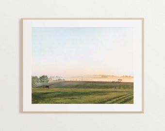 May include: A photograph of a misty field with a few trees in the foreground and a farmhouse in the distance. The sky is a soft blue and the sun is shining through the mist.