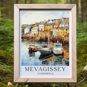 May include: A framed print of Mevagissey, Cornwall, featuring a harbor scene with colorful boats and buildings. The artwork has a painterly style, with a light wooden frame. The text "MEVAGISSEY CORNWALL" is printed at the bottom.