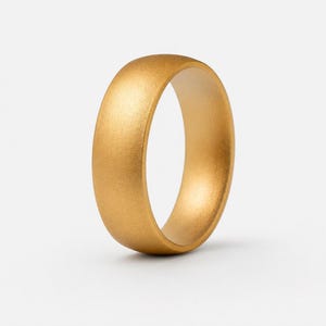Peut inclure: Une bague de couleur or massif avec une finition mate lisse et un profil extérieur arrondi. L'anneau présente une épaisseur constante et une texture métallique uniforme sur toute sa surface, affichant un design circulaire simple sans ornements.