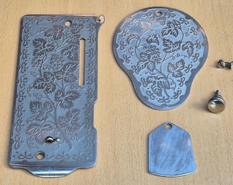 May include: A rectangular metal sewing machine needle plate and a rounded cover plate, both featuring an engraved grape vine pattern. Included are a small plain metal shield-shaped plate, one small screw, and one round metal knob with a threaded post.