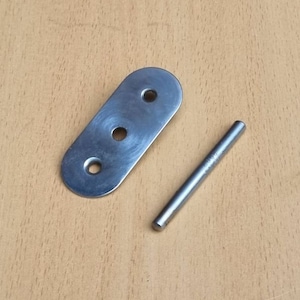 Könnte beinhalten: Ein silbernes Metallscharnier mit drei Löchern und einem silbernen Metallstift. Das Scharnier ist oval geformt und der Stift ist gerade.