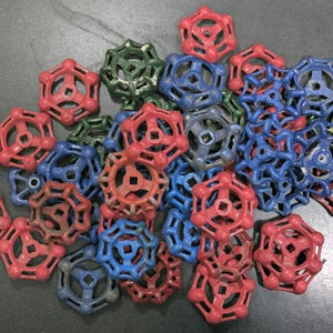 May include: A collection of colorful, vintage water valve handles in red, blue, and green. The handles have a star-like design with a central square opening. These are likely replacement parts for plumbing or industrial applications.