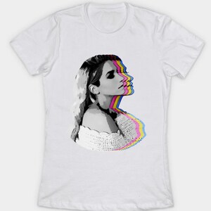 May include: A white t-shirt with a black and white image of a woman's face with a colorful, layered effect. The woman's face is in profile and she is looking to the right. The colors of the layers are pink, yellow, blue, and cyan.