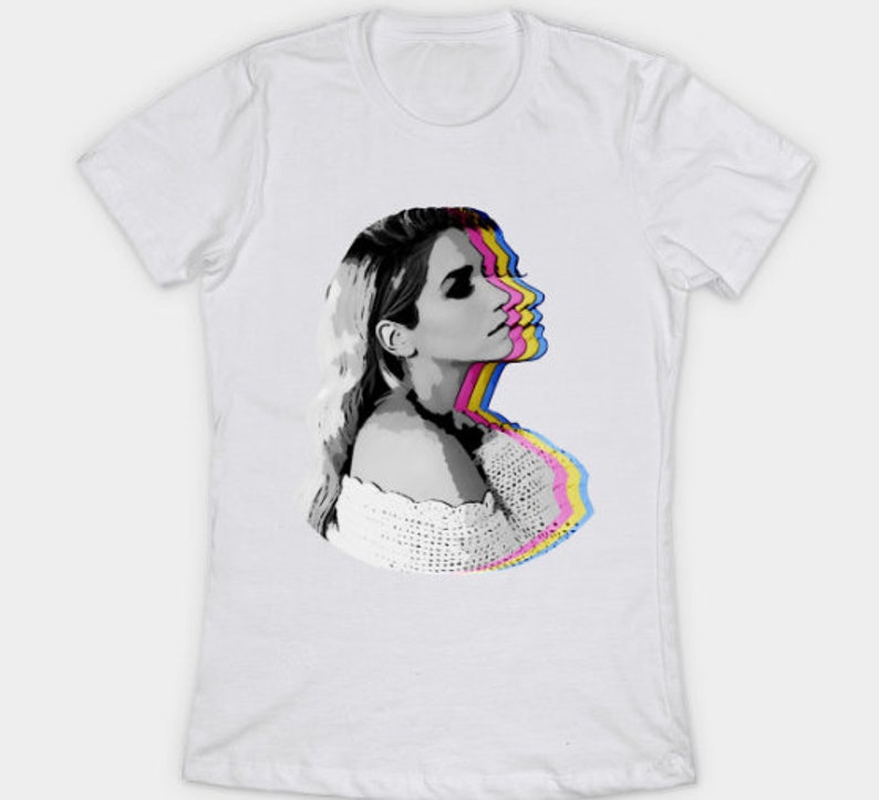May include: A white t-shirt with a black and white image of a woman's face with a colorful, layered effect. The woman's face is in profile and she is looking to the right. The colors of the layers are pink, yellow, blue, and cyan.
