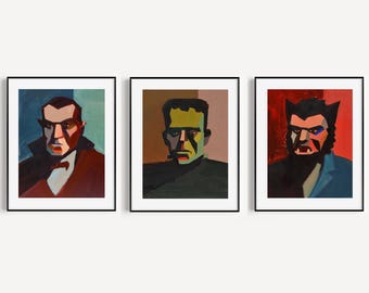 May include: Three framed art prints displaying stylised portraits of iconic horror film characters. The first shows a figure in a red suit with a bow tie, the second a green-skinned figure, and the third a werewolf.
