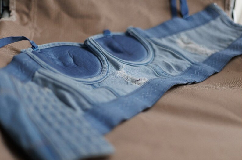 May include: A blue denim bra with a padded cup and adjustable straps.
