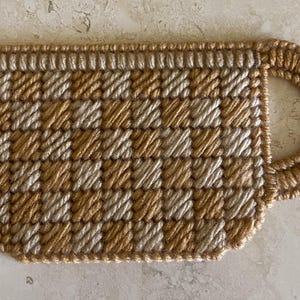 Pu&ograve; includere: Un sottobicchiere per tazza in crochet marrone e beige con un motivo a scacchi.
