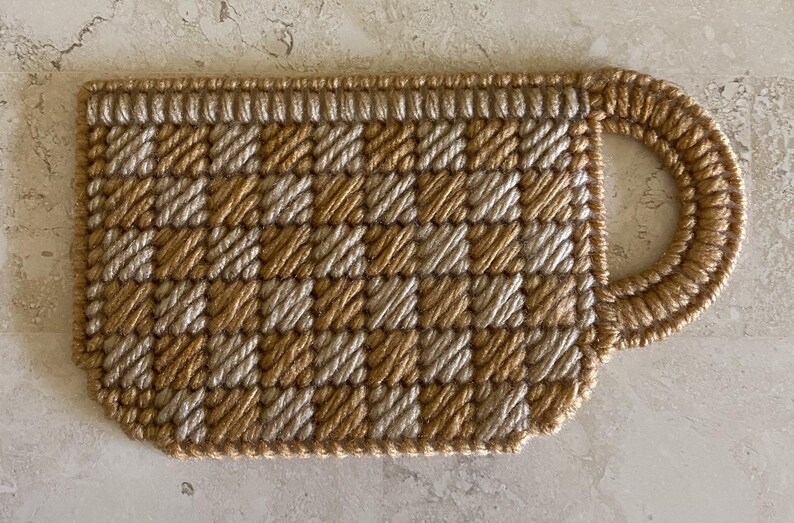 Pu&ograve; includere: Un sottobicchiere per tazza in crochet marrone e beige con un motivo a scacchi.