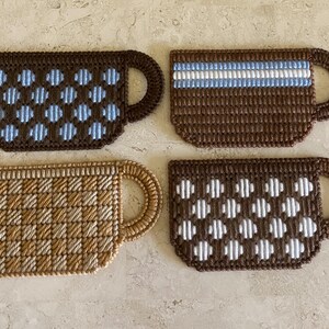 Pu&ograve; includere: Quattro sottobicchieri da caff&egrave; in crochet marroni con diversi motivi. I sottobicchieri presentano pois blu e bianchi, un motivo a scacchi marroni e bianchi, una striscia bianca e pois bianchi.